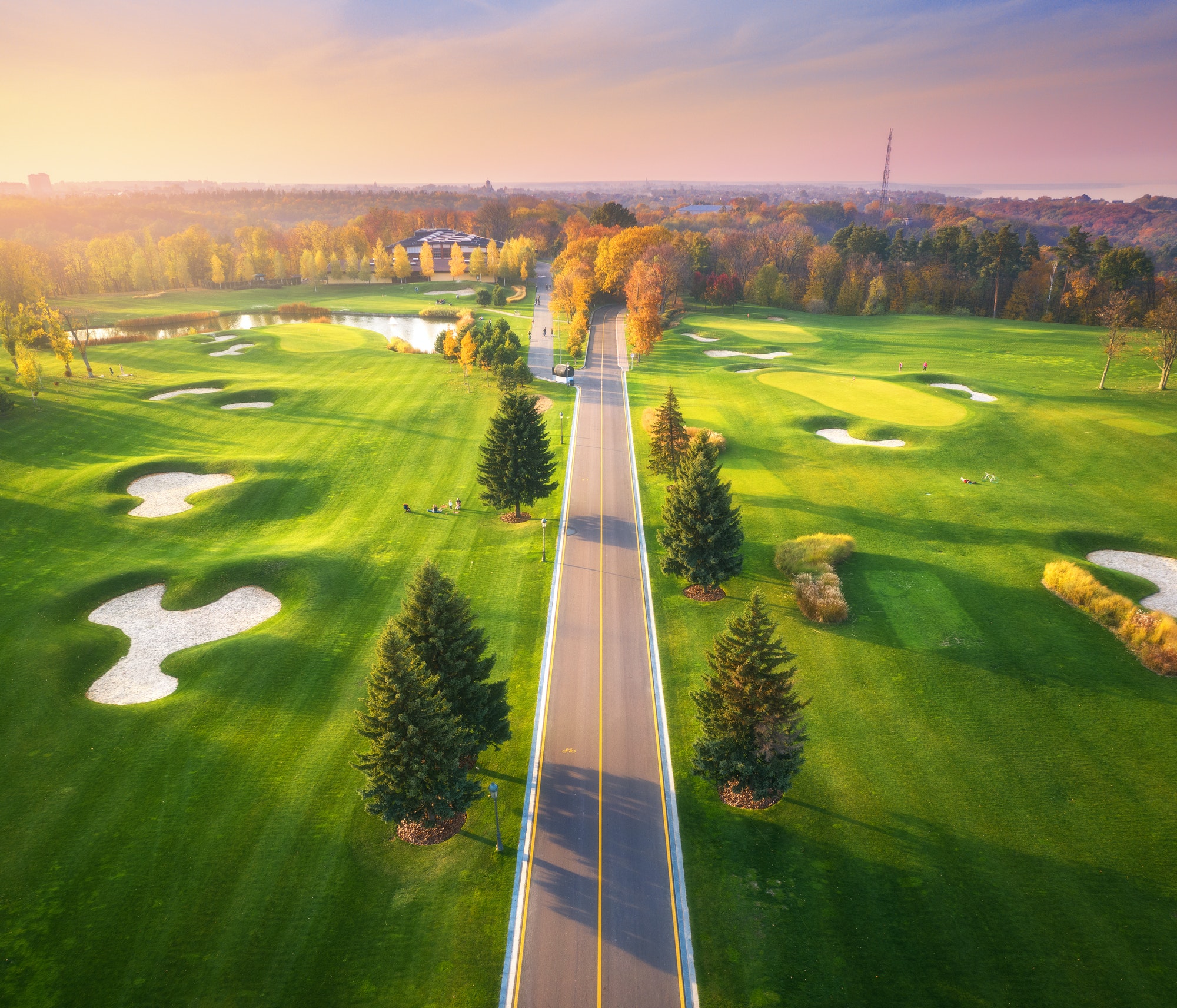 Road through the golf course at sunset in autumn. Aerial view